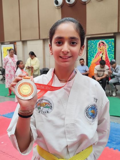 One of our talented yellow-belt students proudly displays her silver medal. We celebrate every achievement, as each step on the podium is a step forward in an athlete's journey.