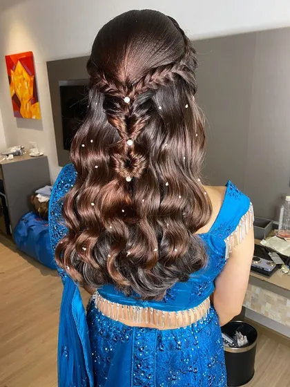 A beautiful half-updo with a fishtail braid detail and soft waves, decorated with small pearl accessories. A perfect Sangeet or Mehendi look.