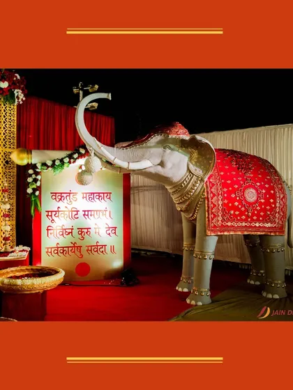 An elephant statue adorned with a traditional red cloth and a scroll with a Sanskrit prayer. This detail adds a deep sense of culture and blessings to the wedding.
