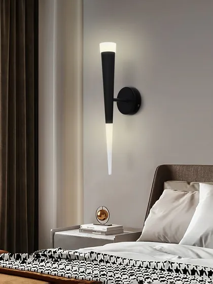 Placed next to a bed, this sconce serves as a stylish and functional reading light. Its design is modern and unobtrusive.