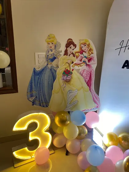 A close-up of the Disney Princess cutouts and the illuminated number '3' from the princess-themed party.