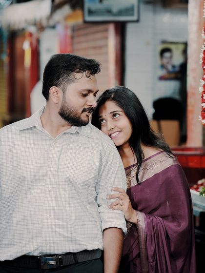 An intimate and sweet moment with the bride leaning on the groom's shoulder, captured in the warm, ambient light of a city market at dusk.
