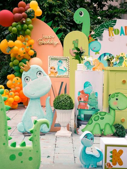 A close-up of the 'One-O-Saurus' setup, highlighting the crowned dinosaur prop and the vibrant balloon garland.