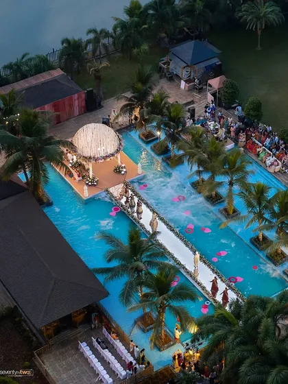 An aerial drone shot capturing the scale and beauty of the poolside wedding setup in Karjat, with the mandap looking like a floating island of flowers.