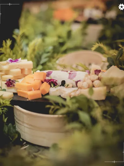 Our artisanal grazing tables are a feast for the eyes and the palate. This close up shows a curated selection of cheeses nestled amongst fresh greenery, an invitation for guests to gather and connect over shared plates.