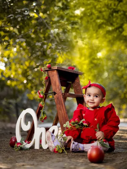 A sweet pose with a rustic ladder and red apples. This setup is perfect for an autumn-themed first birthday.