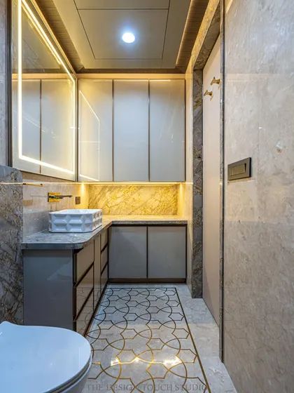This bathroom features premium marble walls, a statement geometric countertop basin, and elegant gold accents. The floor inlay adds a bespoke touch to the design.