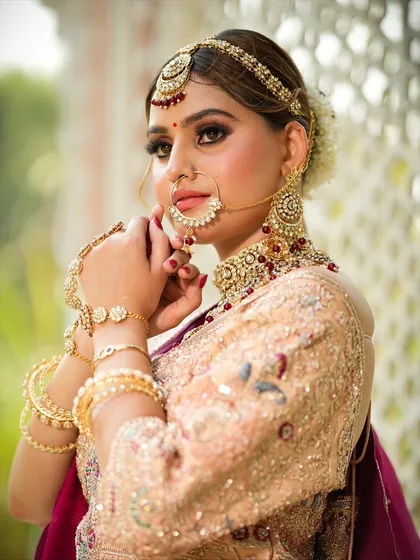 A close-up portrait focusing on the bride's stunning eye makeup and the intricate details of her nose ring and other jewelry.