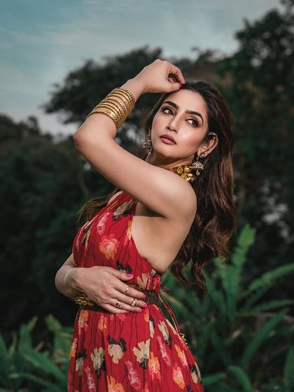 An outdoor portrait with a lush green background. The natural environment adds depth and context to the image, complementing the floral pattern of the dress.