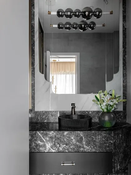 Another view of the powder room, highlighting the custom-designed mirror and the rich texture of the marble. Even in a small space, every detail is considered to create a powerful design statement.