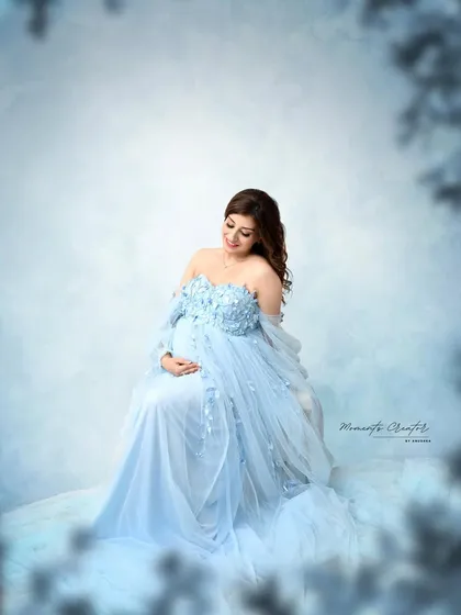 A dreamy, winter-like portrait. The soft blue tones and frosted-like vignette give this image of the mom-to-be in a blue gown a magical, ethereal feel.