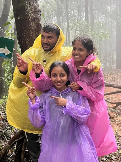 A fun picture with participants pointing at the Kannada sign for the Kurinjal trek route, fully geared up in their raincoats.