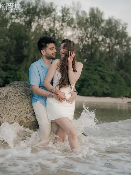 The waves crashing around them, a shared laugh. This photo captures the playful and adventurous side of a beach pre-wedding shoot in Phuket, Thailand.