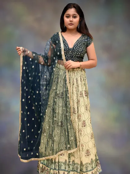 A unique and elegant choice, this lehenga pairs a bottle green mirror-work blouse with a printed pastel yellow and green skirt. It's a sophisticated look for any wedding function.