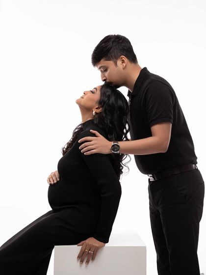 A tender moment between partners. He kisses her forehead as she leans back, a beautiful expression of love and support.