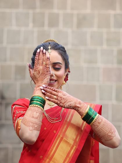 A creative pose showing off the detailed henna art. The makeup is kept soft and radiant, with a focus on flawless skin and expressive eyes.