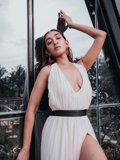 An artistic and elegant pose against a glass window, with the reflection of the sky adding another layer to the image.