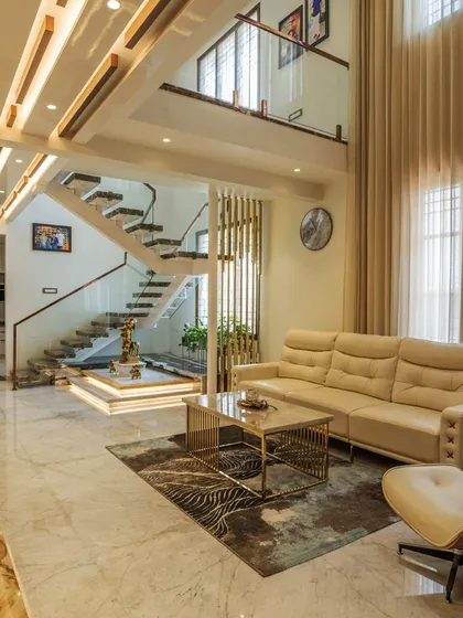 The double-height living room of the "Opulent Abode," with a stunning staircase and a comfortable seating arrangement, creates a grand yet inviting atmosphere.