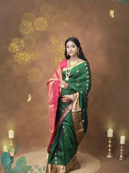 A full-length solo portrait in a beautiful green silk saree. This shot showcases the elegance of traditional wear for a maternity session, set against a warm, classic backdrop.