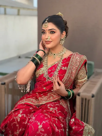 A seated bride in a red saree, her layered temple jewellery creating a look of regal elegance.
