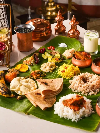 An elegant Onam Sadhya spread on a banana leaf, with traditional copperware and a clean, white background. This composition blends authenticity with a modern, minimalist aesthetic.