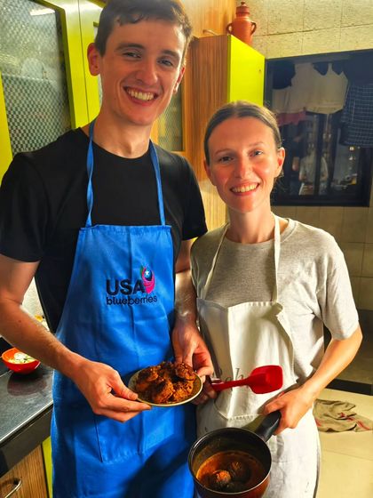 A couple proudly showing off the dishes they cooked from scratch in my kitchen. They learned to make a rich curry and a spicy dry dish, ready to take the recipes home with them.