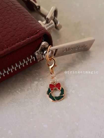 A close-up of the Christmas wreath bag zip charm, attached to a red wallet. It's a simple way to make your accessories festive.