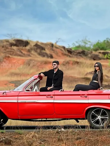 A stylish pre-wedding shoot featuring a couple with a vintage red convertible against a rustic, open landscape. This showcases my ability to arrange unique props and locations for a cinematic feel.