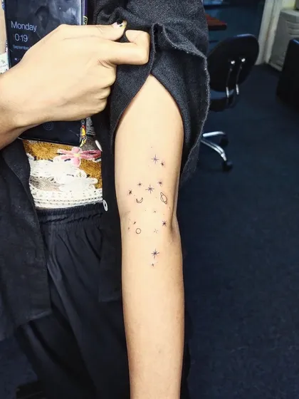 A delicate constellation of stars and symbols on the arm. This fine-line piece is like a personal map of the cosmos, unique to the wearer.