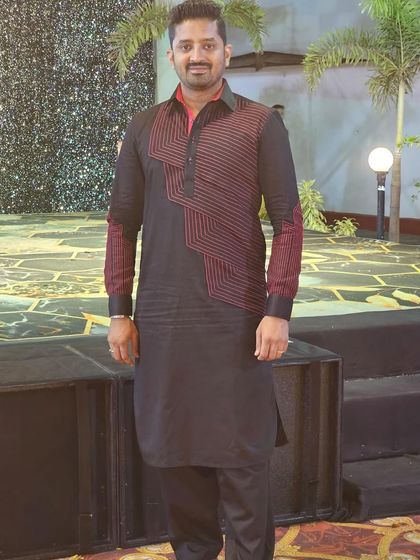 A client at an event in a black Pathani-style kurta with a striking red geometric pattern. This is a bold, modern, and confident look.