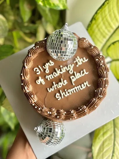 "31 yrs of making the whole place shimmer." This fun chocolate birthday cake is topped with disco balls, perfect for someone who adds a little extra sparkle to life.