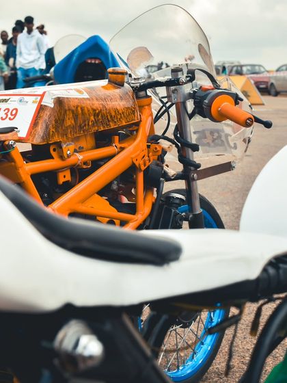 A close-up of a custom-built drag bike with an orange frame, showcasing the intricate details of its construction.