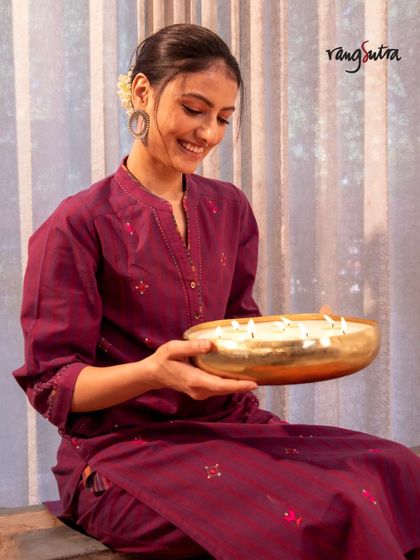 A model holding a bowl of floating candles, wearing our Haveli Soof-embroidered kurta. This image perfectly captures the festive spirit of the collection.