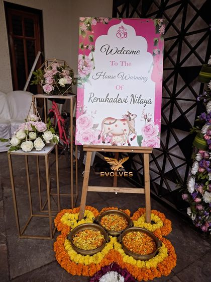 The welcome board setup for a house warming ceremony, featuring a custom-designed sign, floral arrangements, and traditional elements.