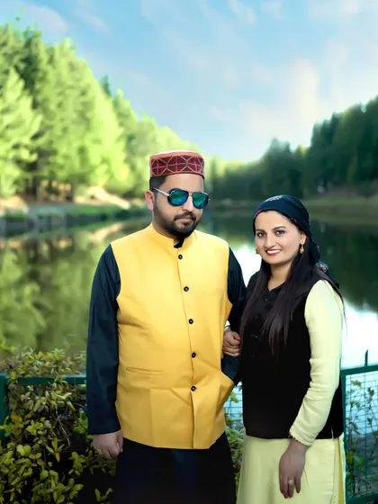 A couple's portrait taken by a serene mountain lake. The man wears a Himachali cap, adding a touch of local culture to this beautiful and relaxed pre-wedding photography session.
