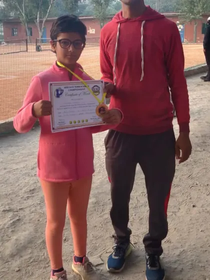 A player showing her medal and certificate. Every competition is a learning experience, and every win is a milestone.