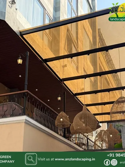A look from below the pergola, highlighting the tinted glass roof and the warm ambiance created by the hanging wicker lamps and street-style lanterns.
