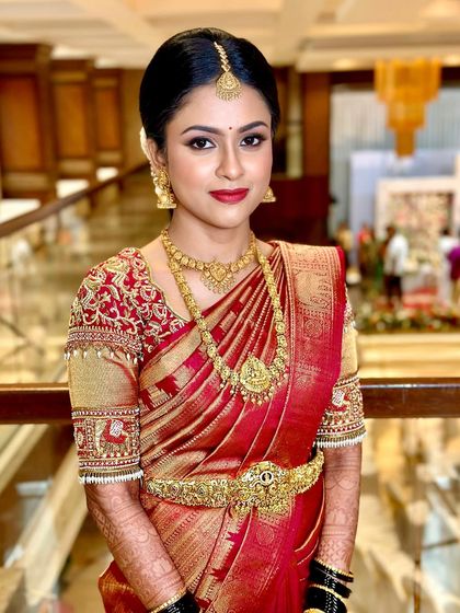 A classic South Indian bridal look featuring a bold red lip and defined eyes. This makeup style is perfect for the bride who wants to make a statement while looking traditionally elegant in her red and gold Kanjivaram.