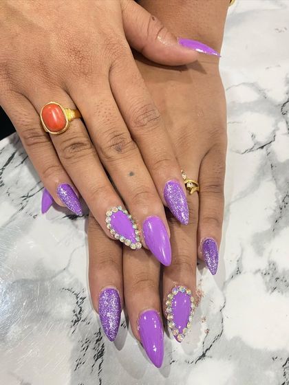 This bold purple set is perfect for making a statement. It combines a glossy purple polish with purple glitter and large heart-shaped rhinestone clusters on the accent nails.