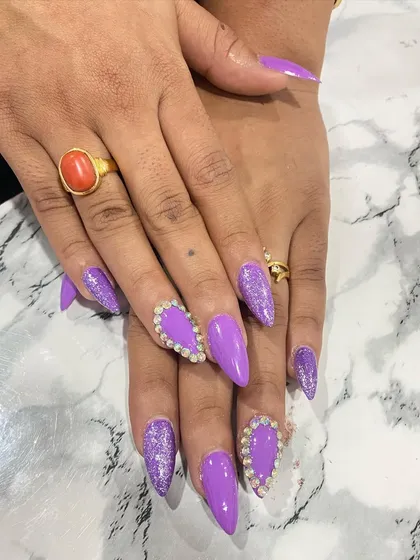 This bold purple set is perfect for making a statement. It combines a glossy purple polish with purple glitter and large heart-shaped rhinestone clusters on the accent nails.