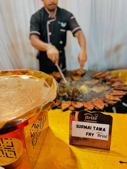 A chef in action, frying Surmai fillets on a large tawa, a popular live station at many weddings.