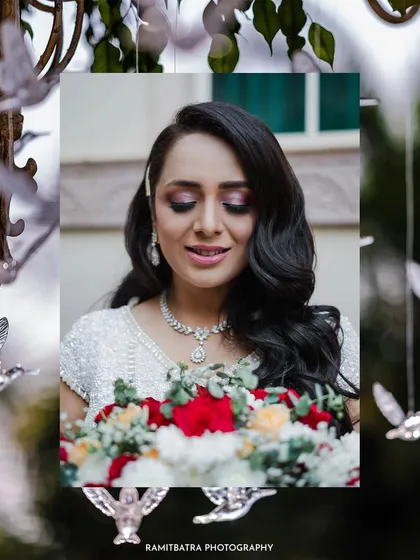 A beautiful portrait of the bride at her white-themed wedding celebration in Delhi, holding a bouquet of red and white roses.