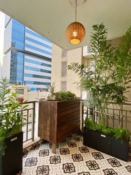 This custom-designed wooden bar cabinet provides stylish outdoor storage. The slatted design is modern and functional, and it serves as a beautiful base for displaying plants and decor against the urban backdrop.