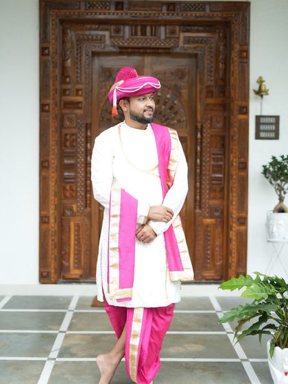 A groom looking elegant in our white sherwani and pink dhoti set. This traditional attire is perfect for wedding rituals and is available for rent at an affordable price.
