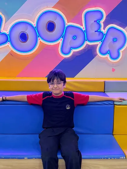 A student takes a break from the action, relaxing in front of our cool neon Zooper sign.
