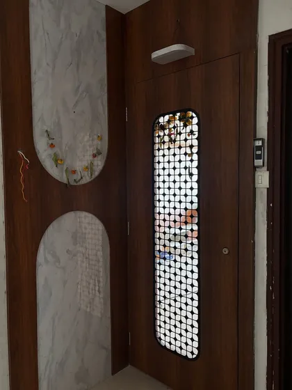 An entrance design combining a dark wood safety door with a white marble-paneled wall feature.
