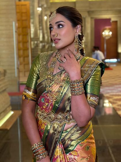 A candid, side-profile shot that captures the richness of the silk saree and the elaborate jewellery.