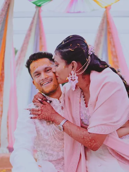 A candid moment from the Haldi ceremony, capturing a sweet kiss on the cheek.