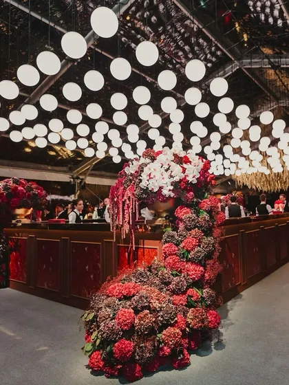 A stunning, oversized bar was the centerpiece of this glamorous cocktail night. The bar was adorned with massive red and white floral arrangements, and the ceiling featured a custom installation of glowing orbs.
