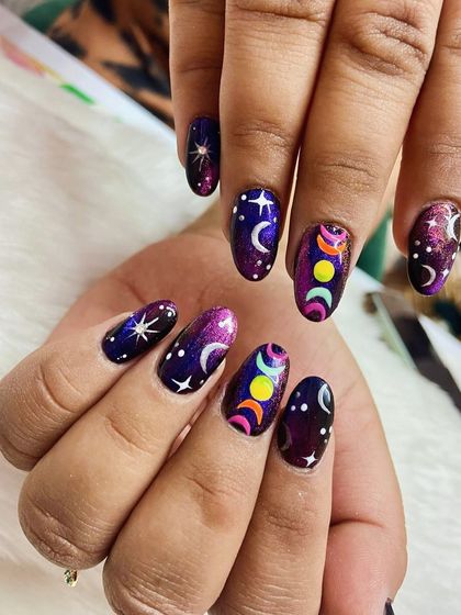 Cosmic vibes only. Manifesting magic with these galaxy-inspired nails, featuring moon phases, stars, and a beautiful purple and deep blue color palette.